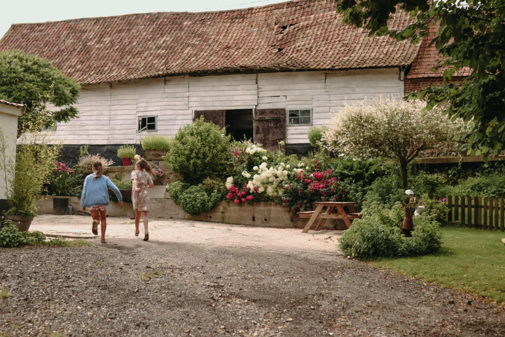 Fillettes qui courent devant bâtiment de ferme fleuri